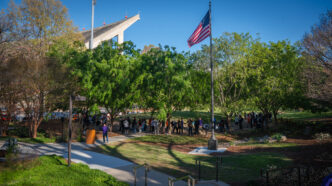 Attendees circle a large mound at the Scroll of Honor Memorial