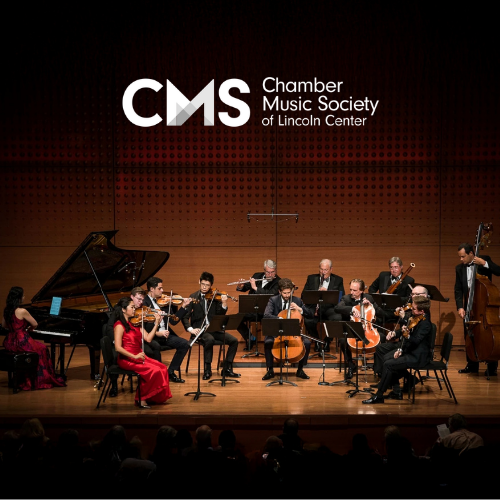 A large ensemble of musicians perform on stage in formal wear