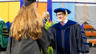 College of Arts and Humanities Dean Nicholas Vazsonyi shakes a student's hand at graduation