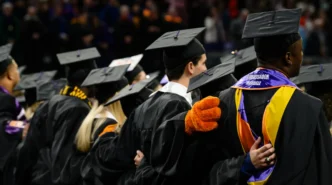 Students stand shoulder to shoulder at their commencement ceremony, singing the alma mater dressed in their caps and gowns.
