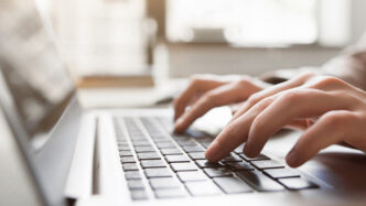 Closeup of hands typing on laptop