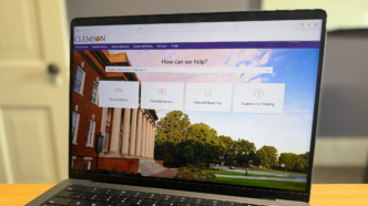 A laptop sits on a desk displaying a ServiceNow portal.