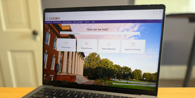 A laptop sits on a desk displaying a ServiceNow portal.