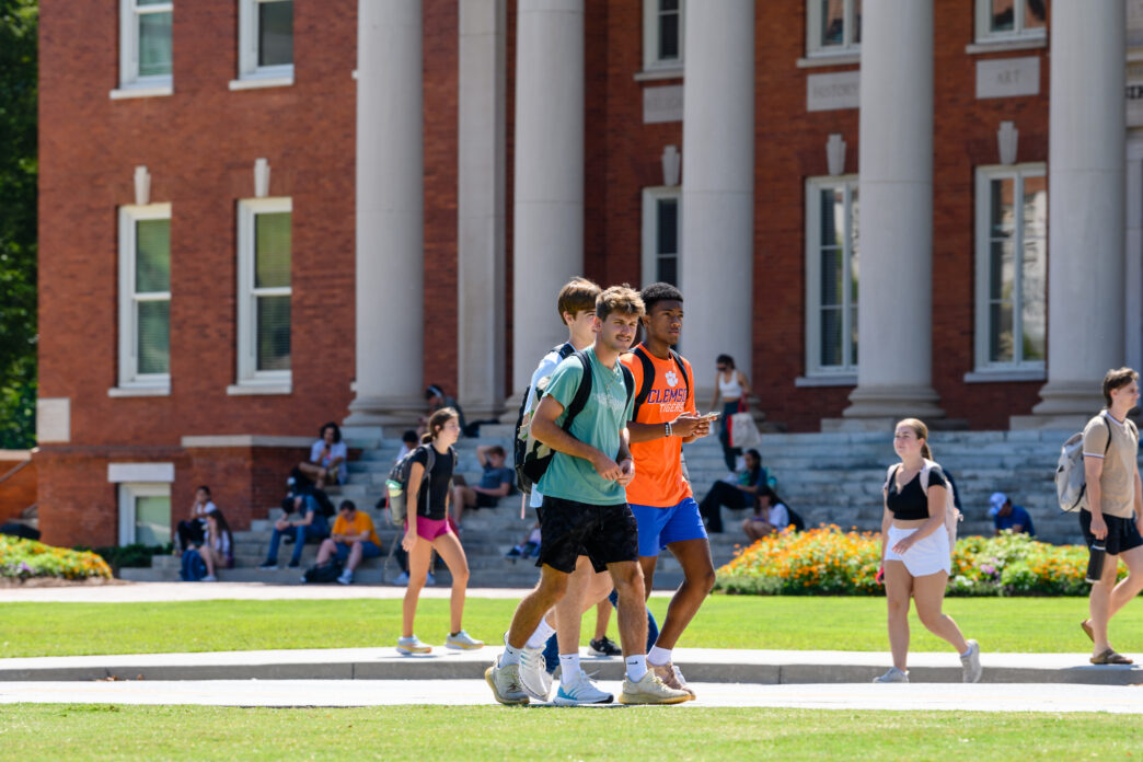 students walking on front of a bid, columned brick building