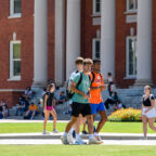 students walking on front of a bid, columned brick building