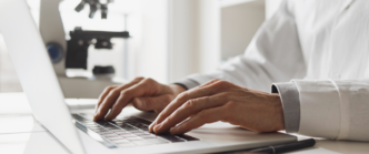 Close up of hands using a laptop in a research lab.