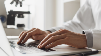 Close up of hands using a laptop in a research lab.