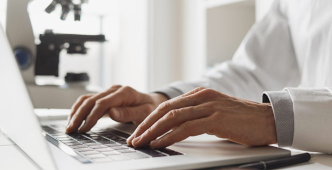 Close up of hands using a laptop in a research lab.