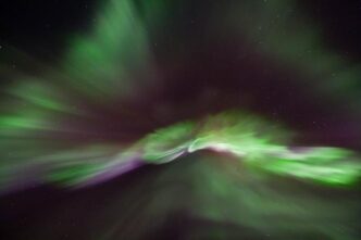 A photo of the aurora borealis showing green and purple light in a black sky.