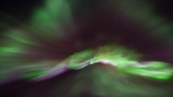 A photo of the aurora borealis showing green and purple light in a black sky.
