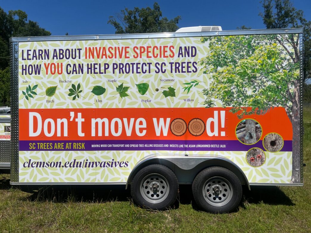 A trailer wrapped with various Clemson-centric messages reminding people to not move wood.