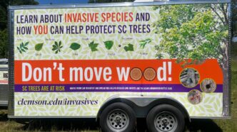 A trailer wrapped with various Clemson-centric messages reminding people to not move wood.
