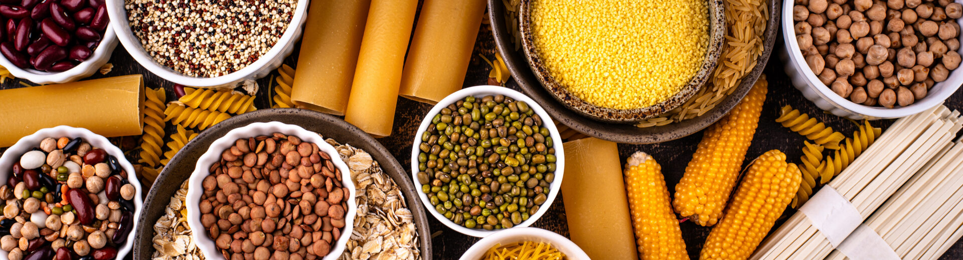 A photo that shows bowls f different sources of carbs in food, including pasta, corn, beans.
