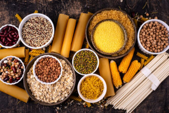 A photo that shows bowls f different sources of carbs in food, including pasta, corn, beans.