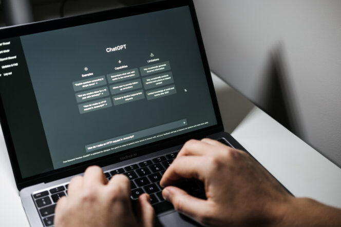 Hands type a prompt on a laptop into a ChatGPT text box.