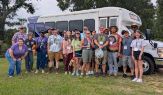 Participants in the organic certification workshop stand inffront of their bus.
