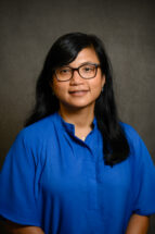 Head shot of a woman wearing a blue top and glasses with dark hair (Thao Tran Dominy)