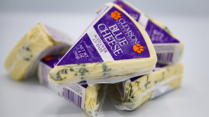 several wedges of blue cheese, wrapped in Clemson Blue Cheese packaging, stacked on top of each other