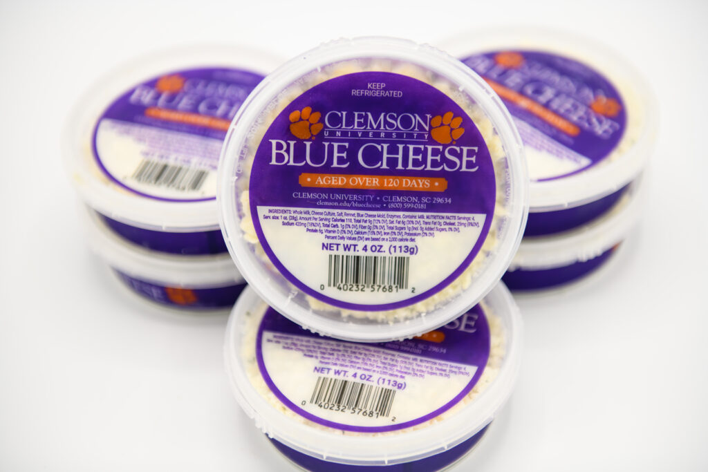 three stacks of two small tubs of crumbled blue cheese with Clemson Blue Cheese packaging