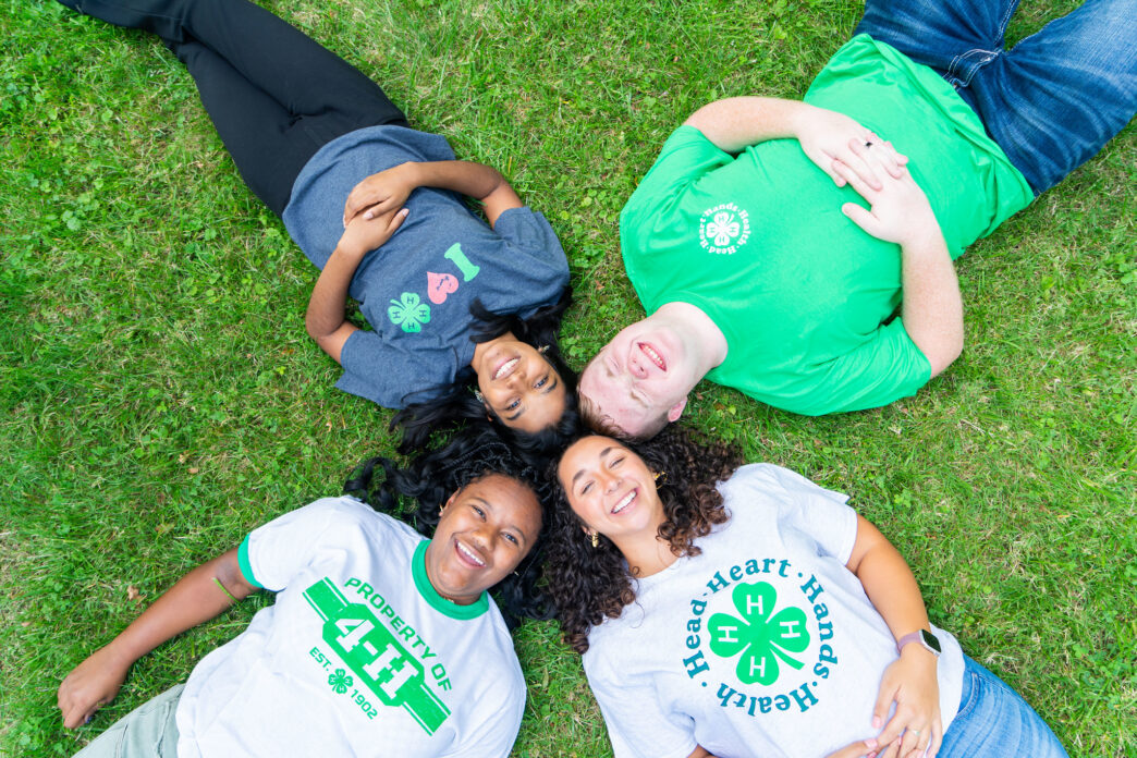 Four youth laying in a circle