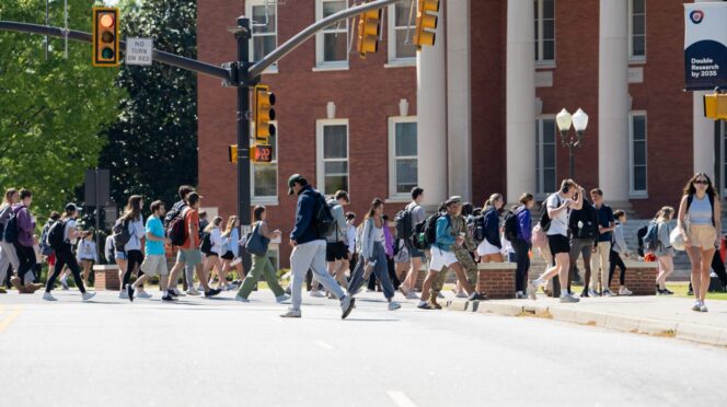 Students walking in front of a brick, columned building