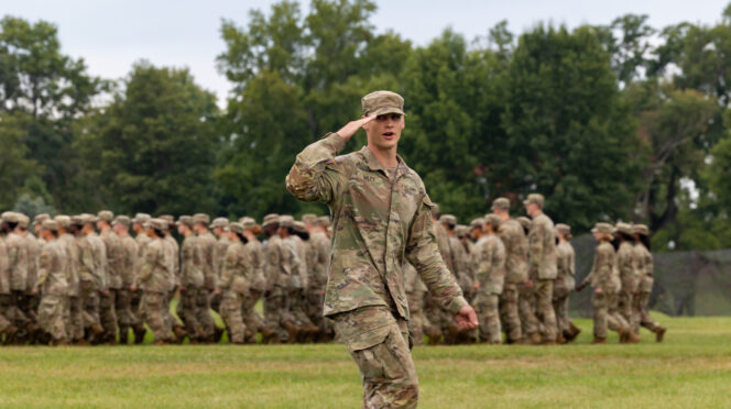 Army RTOC cadet salutes while leading a company behind
