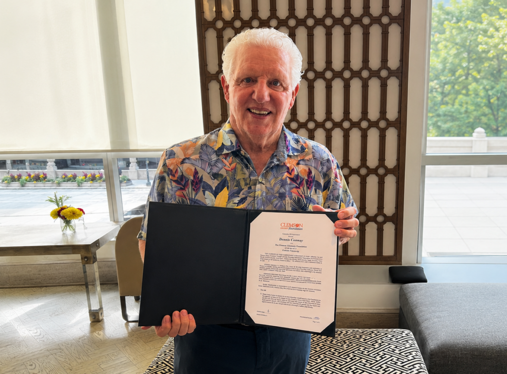Dennis Conway holding his endowment folder showcasing his commitment to funding the Roofing Alliance