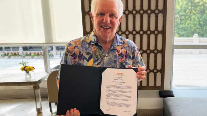 Dennis Conway holding his endowment folder showcasing his commitment to funding the Roofing Alliance
