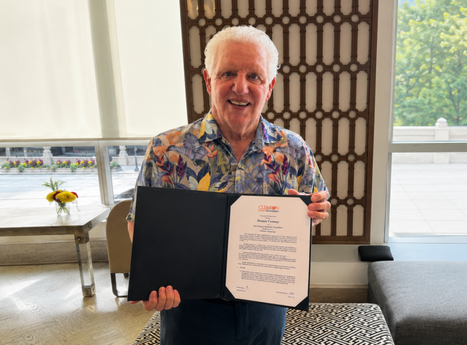 Dennis Conway holding his endowment folder showcasing his commitment to funding the Roofing Alliance