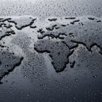 World map formed by water droplets on dark surface, global environment and climate change concept, liquid earth silhouette with moisture texture