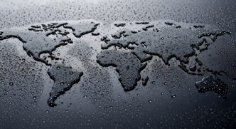 World map formed by water droplets on dark surface, global environment and climate change concept, liquid earth silhouette with moisture texture