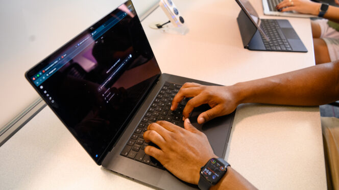 Hands type a prompt into ChatGPT on a laptop.