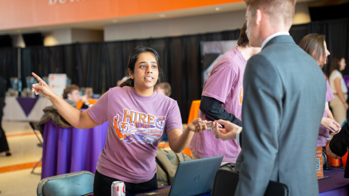 A female in a t-shirt gives instructions to a male in a suit