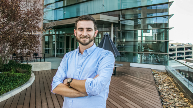 Jake Coplin, a white man with brown hair, MBA student and cyclist, stands in front of Greenville ONE.