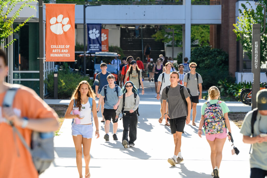 Students walk past signs for the College of Arts and Humanities