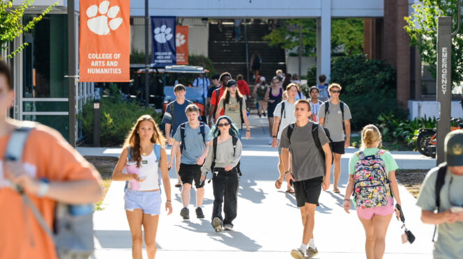 Students walk past signs for the College of Arts and Humanities