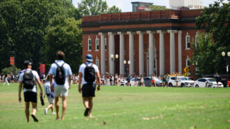 Students walk across Bowman Field toward Sikes Hall on Clemson University's campus.