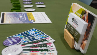 Interpersonal violence prevention and response resources are laid out on a table with a dark green tablecloth as part of an Interpersonal Violence Response event.