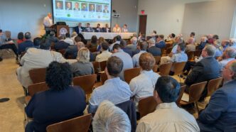 A room filled with people watching a presentation.
