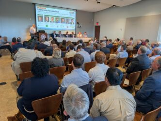 A room filled with people watching a presentation.