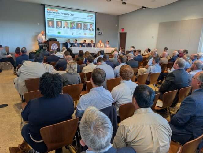 A room filled with people watching a presentation.