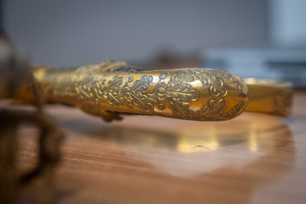 A close-up of the intricate designs on the brass handle of a sword