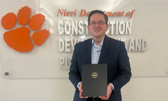Industry leader Trent Cotney smiles in front of the Nieri Department of Construction and Real Estate Development sign