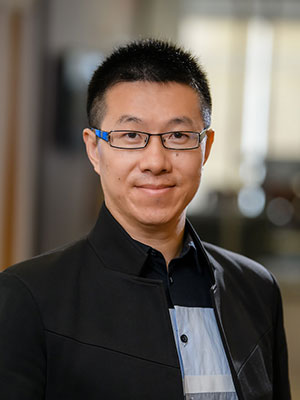 A man wearing glasses and black suit coat