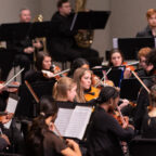 Musicians perform on stage in an orchestra