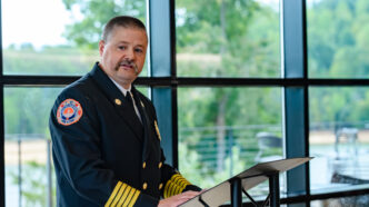 CUFD Chief William Moreland stands at a podium and delivers remarks during a ceremony.