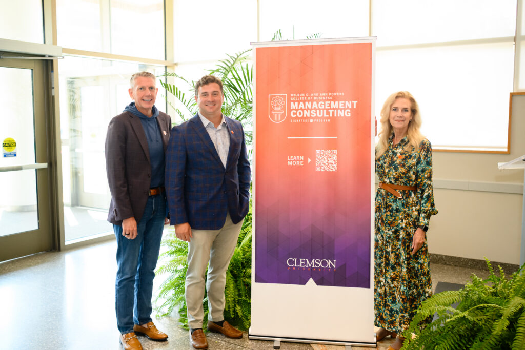 Dirk Roskam, Matt Hersel and Wendy York pose with Management Consulting pop-up banner