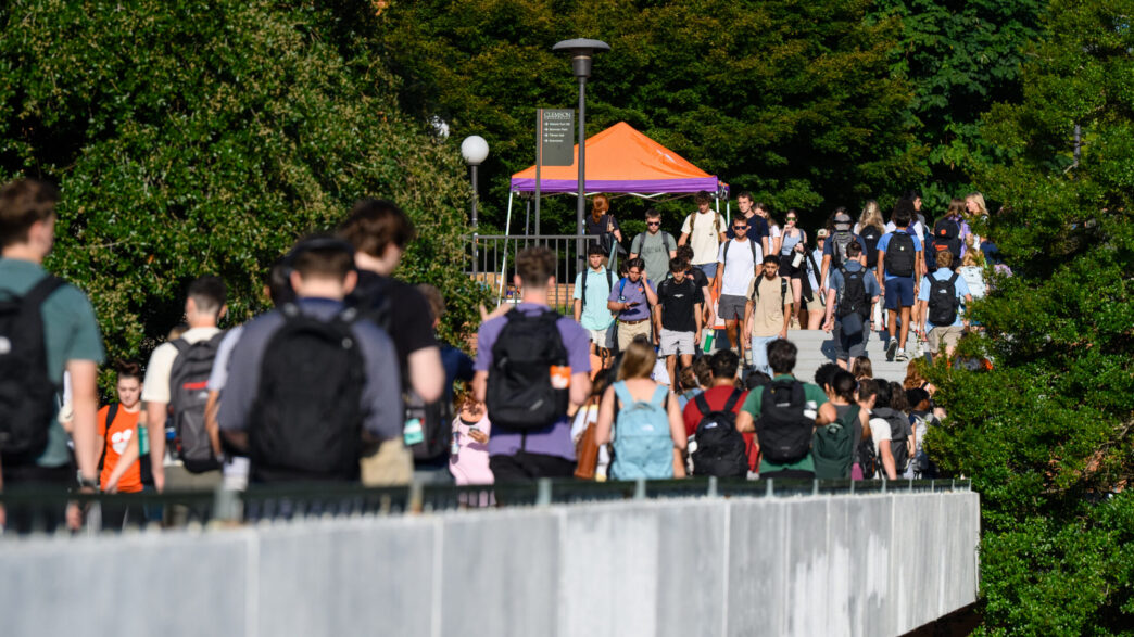A large group of student walk through campus during class change.