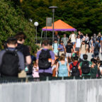 A large group of student walk through campus during class change.