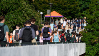 A large group of student walk through campus during class change.